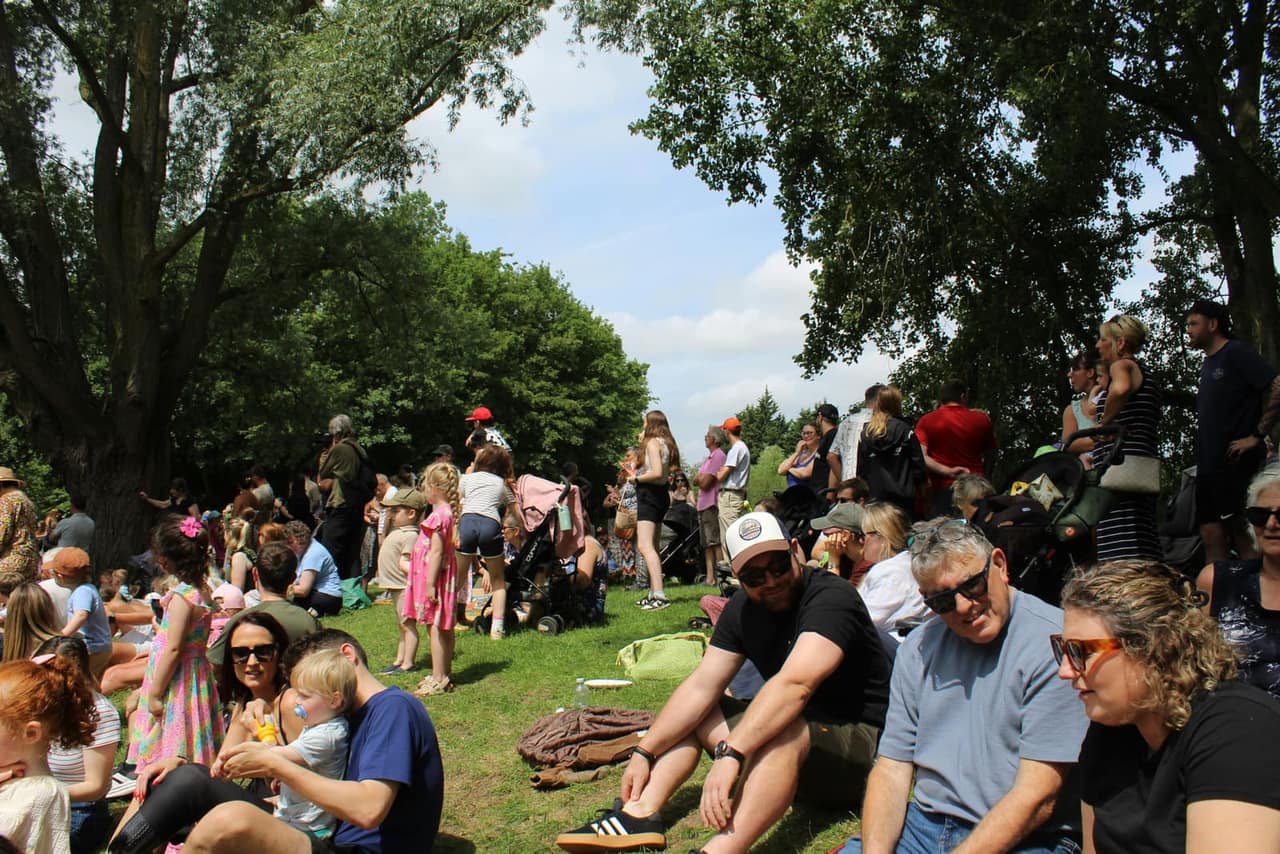 A crowd gathered on the grass under the trees.