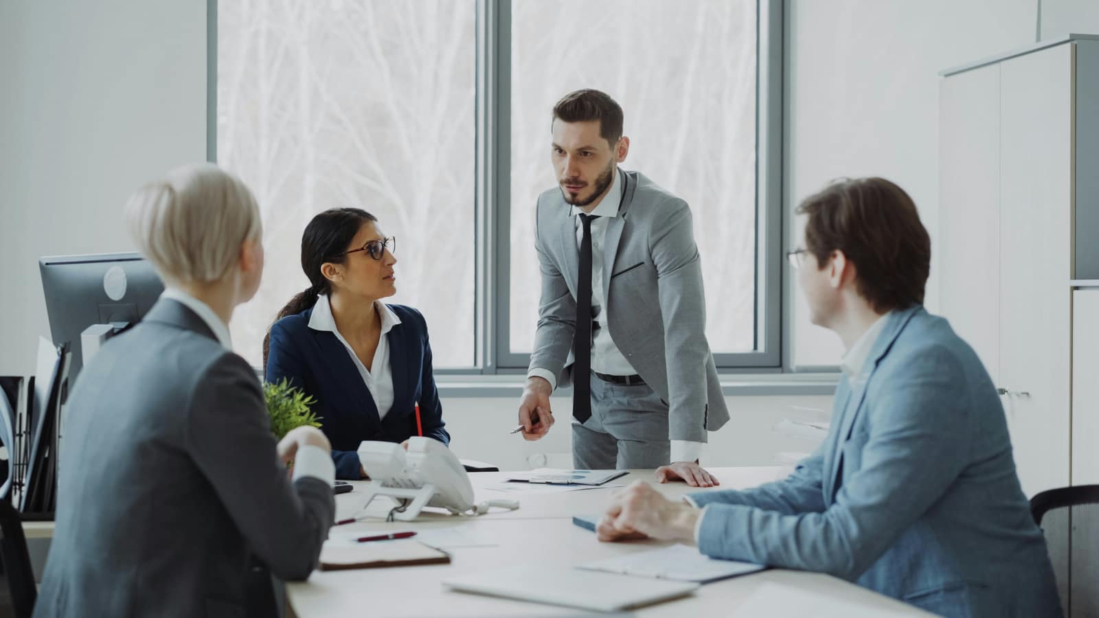 Colleagues meeting around a table in a bright office.